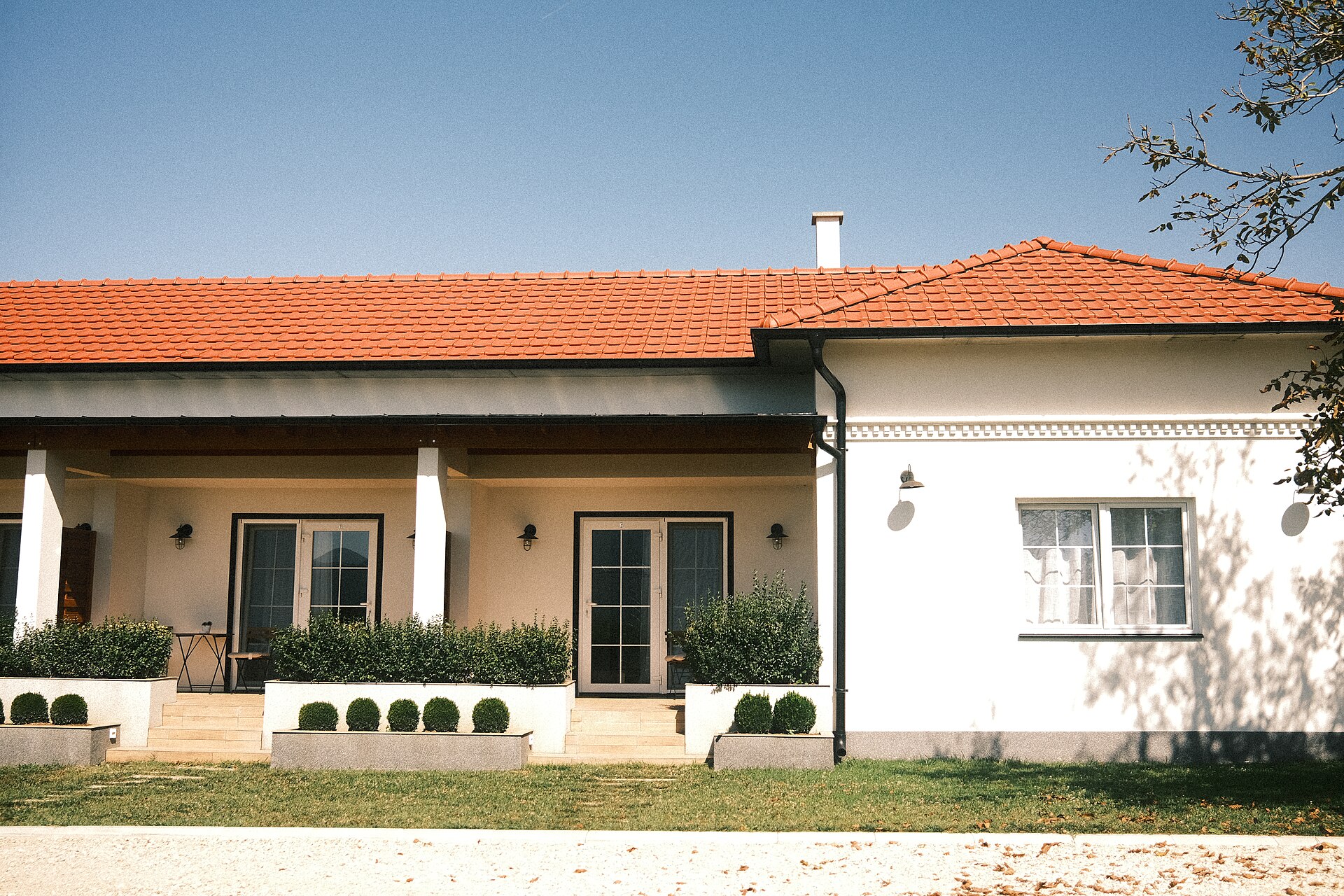 Casa de fachada blanca con tejado rojo y jardín.
