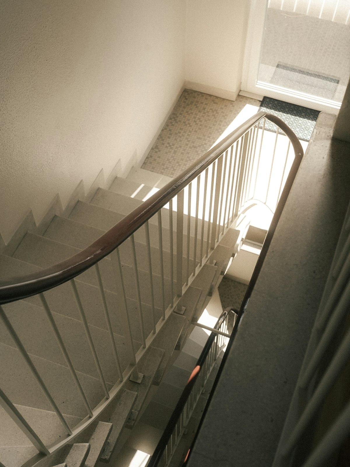 Escalera luminosa de un edificio de viviendas con barandilla blanca.